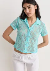 Camisa de manga corta color turquesa, confeccionada en tela de encaje con diseño floral. Presenta cuello camisero y cierre frontal con botones.