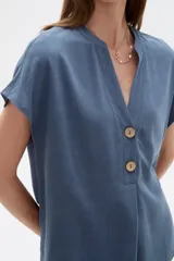 Blusa de viscosa color blanco, de corte holgado, con cuello en V y cierre frontal parcial de botones grandes con efecto carey.
