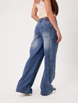 Jean wide leg de tiro alto color celeste, con diseño estampado tipo paisley en los laterales de las piernas.