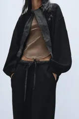 Pantalón de punto de tiro alto con bolsillos delanteros y bolsillos de plastrón en la parte trasera. Presenta una cintura doble ajustable con cordón en tejido a contraste.