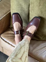 Zapatos tipo Mary Jane con punta cuadrada, confeccionados en cuero con estampado de vaca (animal print) y tira ajustable con hebilla metálica en color marrón.