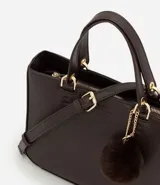 Cartera satchel mediana color beige, con cierre de cremallera, correa de mano y bretel largo desmontable. Incluye un llavero de pompón de piel sintética.