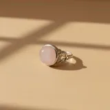 Anillo de plata 925 con piedra central de cuarzo rosa en corte cabujón y banda con diseño trenzado.