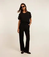 Blusa negra de crepé con cuello redondo y mangas cortas decoradas con lazos aplicados.