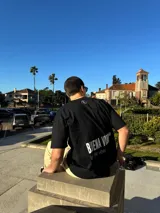 Remera de corte semi oversize en color beige, con estampado gráfico en la espalda que incluye la frase 'BUENA VIBRA' en letras grandes y 'feel the vibes' en tipografía cursiva, además de un pequeño logo bordado en la nuca.