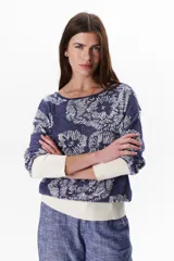 Sweater de tejido de punto con diseño floral, confeccionado en una mezcla de algodón y lurex. Presenta cuello redondo, mangas largas con puños anchos en color crema y un calce holgado.