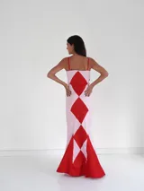 Vestido largo de corte sirena con diseño de rombos en colores púrpura y rojo. Presenta breteles finos, escote recto y una falda con caída fluida y cola corta.