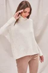 Sweater de punto color crema, con cuello alto y mangas largas.