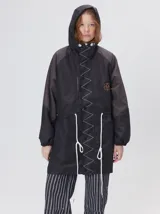 Campera tipo piloto con capucha, cierre frontal con botones y detalle de costuras en zigzag. Presenta cordones ajustables en la cintura y capucha, puños elásticos y logo bordado en el pecho.