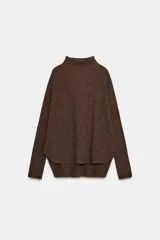 Jersey de punto color marrón con cuello subido y manga larga. Presenta un diseño de cuerpo amplio estilo capa con sisa ancha y bajo asimétrico con aberturas laterales.