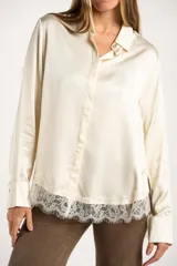 Camisa de satén color arena, de corte clásico con cuello camisero, manga larga con puños abotonados y detalle de encaje en el ruedo.