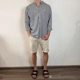 Camisa de algodón con cuello mao y estampado de rayas verticales finas. Presenta cierre frontal con botones y logo bordado en el pecho.