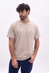 Remera oversize color beige de manga corta, con cuello redondo y un pequeño parche bordado en el pecho.