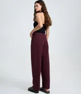 Pantalón baggy de sarga color bordó, con cintura tradicional, cierre de botón y cremallera, bolsillos curvos y corte recto y holgado.