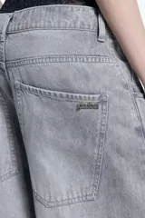 Jean de denim color gris con calce barrel, de pierna levemente bombé y pinzas a la altura de la rodilla. Presenta cierre frontal con botón y bolsillos laterales.