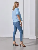 Blusa blanca de gasa marca Zac & Rachel, con frunces en la parte delantera, mangas cortas con puño elastizado, abertura central en la espalda y botón.