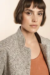 Chaqueta de sastrería color crema, entallada y con cuello erguido. Prenda forrada de lana fina sin teñir.