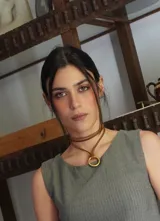 Gargantilla de cuero marrón con dije circular dorado.