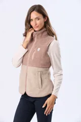 Chaleco de sherpa combinado en tonos beige, con cuello alto y cierre frontal. Presenta una textura suave y abrigada, ideal para capas adicionales.