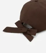 Gorra de sarga marrón con visera curva y detalle de lazo en la parte trasera.