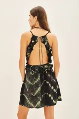 Vestido corto negro con estampado tie-dye en tonos beige/amarillento. Presenta escote en V con volados en el frente y tirantes finos ajustables. Tiene bordados con cuentas en tonos rosados/rojizos en la parte inferior.