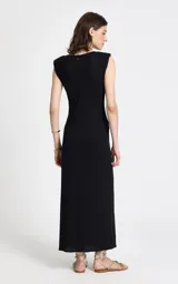 Vestido midi de tejido de punto color negro, con escote redondo, sisas amplias sin mangas, lazo frontal en la cintura y falda recta con abertura frontal.