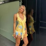 Vestido corto de escote profundo con volados frontales, diseño sin mangas y estampado floral con tonos amarillos y azules.