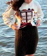 Sweater de punto color blanco marfil con diseño jacquard en el frente que representa una alacena con vajilla, detalles bordados a mano, cuello redondo y manga larga.