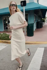 Falda midi de punto color crudo, con tiro medio, cintura elástica y diseño evasé.