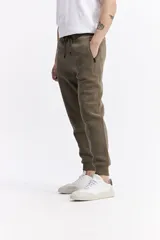 Pantalón de jogging color gris melange, confeccionado en tejido de algodón y poliéster. Presenta cintura elástica con cordón de ajuste, bolsillos laterales con cierre y puños elásticos en los tobillos.