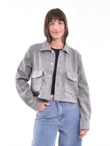 Chaqueta corta gris con cuello camisero, cierre frontal con botones a presión, mangas largas y bolsillos de parche con solapa en el pecho.