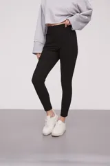 Calza negra de tiro alto con cierre lateral y detalle de costura en la rodilla.