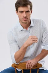 Camisa de manga larga confeccionada en mezcla de lino y algodón, con diseño de rayas verticales celestes y blancas, cuello camisero y cierre frontal de botones.