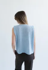 Chaleco de punto calado celeste con diseño estampado en negro y cierre frontal mediante tiras tejidas a crochet.