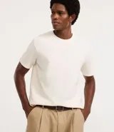Remera de hombre, corte regular, color blanco hueso, con cuello redondo y manga corta. El tejido presenta una textura perforada vertical.