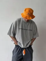 Remera oversize gris con efecto acid wash y estampa frontal con la leyenda "WORLDWIDE TOUR" en tipografía gótica.