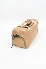 Bolso de viaje gris con doble asa corta y cierre superior. Estampado frontal con la frase "The Tote Bag" en letras blancas.