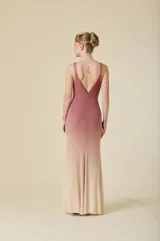 Vestido largo de tul color verde agua, con escote en V, tirantes dobles finos y detalles de pedrería brillante distribuida por toda la prenda. Presenta una silueta ajustada en el torso que se abre suavemente hacia el ruedo.