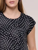 Blusa de gasa ligera con diseño geométrico en tonos oscuros, escote redondo, mangas cortas y bolsillo frontal aplicado. Presenta un ruedo redondeado y silueta relajada.