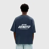 Remera de algodón color azul oscuro, con corte oversize y estampa gráfica en la espalda con el texto 'WE ARE VENEFO' y leyenda complementaria en color blanco.