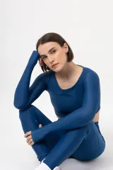 Top azul de lycra con mangas largas tipo guante y cuello redondo.
