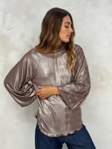 Blusa de manga larga color azul eléctrico con acabado brillante o metalizado, cuello alto y corte holgado.