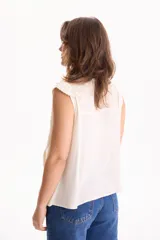 Blusa de viscosa negra sin mangas, con diseño fluido, cuello redondo y detalles de tablas verticales en el pecho con terminaciones de encaje en las sisas.