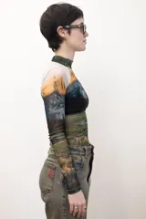 Remera crop top de mangas largas y cuello alto, confeccionada en tejido de red transparente con estampado de paisaje montañoso.