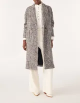 Tapado largo de tejido de punto con diseño de espiga en tonos blanco, negro y gris. Tiene cuello con solapas, doble botonadura y bolsillos laterales.