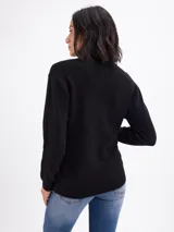Buzo de punto arroz con diseño de ochos, cuello alto y mangas largas.