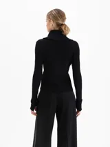 Cardigan de tejido de punto fino con silueta ajustada, cuello alto y cierre frontal de doble camino. Presenta mangas largas con aberturas para los pulgares.