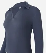 Blusa de manga larga confeccionada en tejido rib de algodón con elastano. Presenta un diseño ajustado al cuerpo con cuello polo y escote en V.