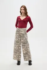 Pantalon de jean de corte ancho y tiro alto, con estampado animal print tipo cebra en tonos beige y gris.