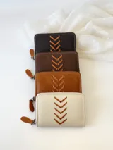 Billetera pequeña de cuero color marrón con cierre metálico y diseño de espiga. Incluye monedero interno.